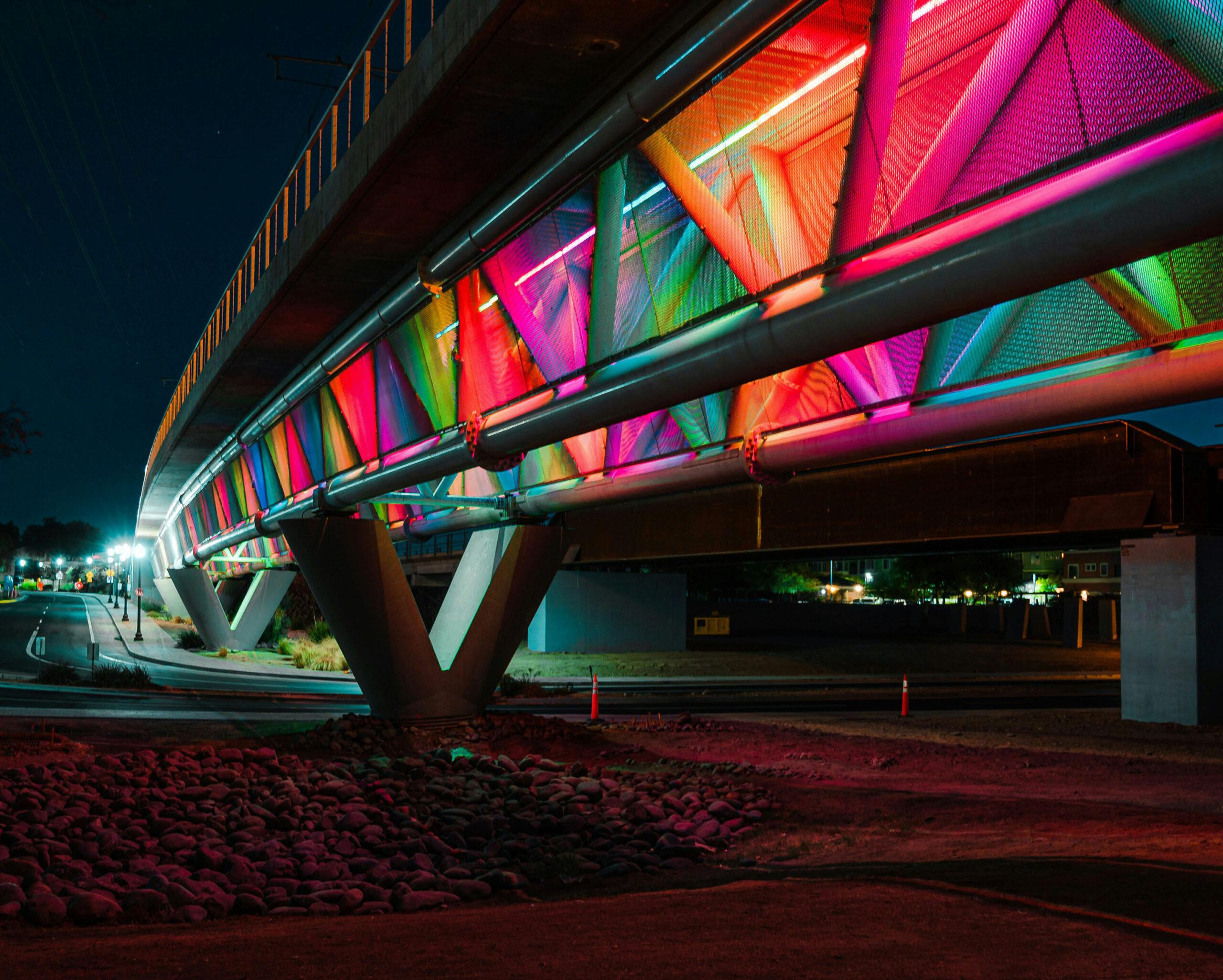 The Tempe Town Lake pedestrian bridge colorfully lit at night.